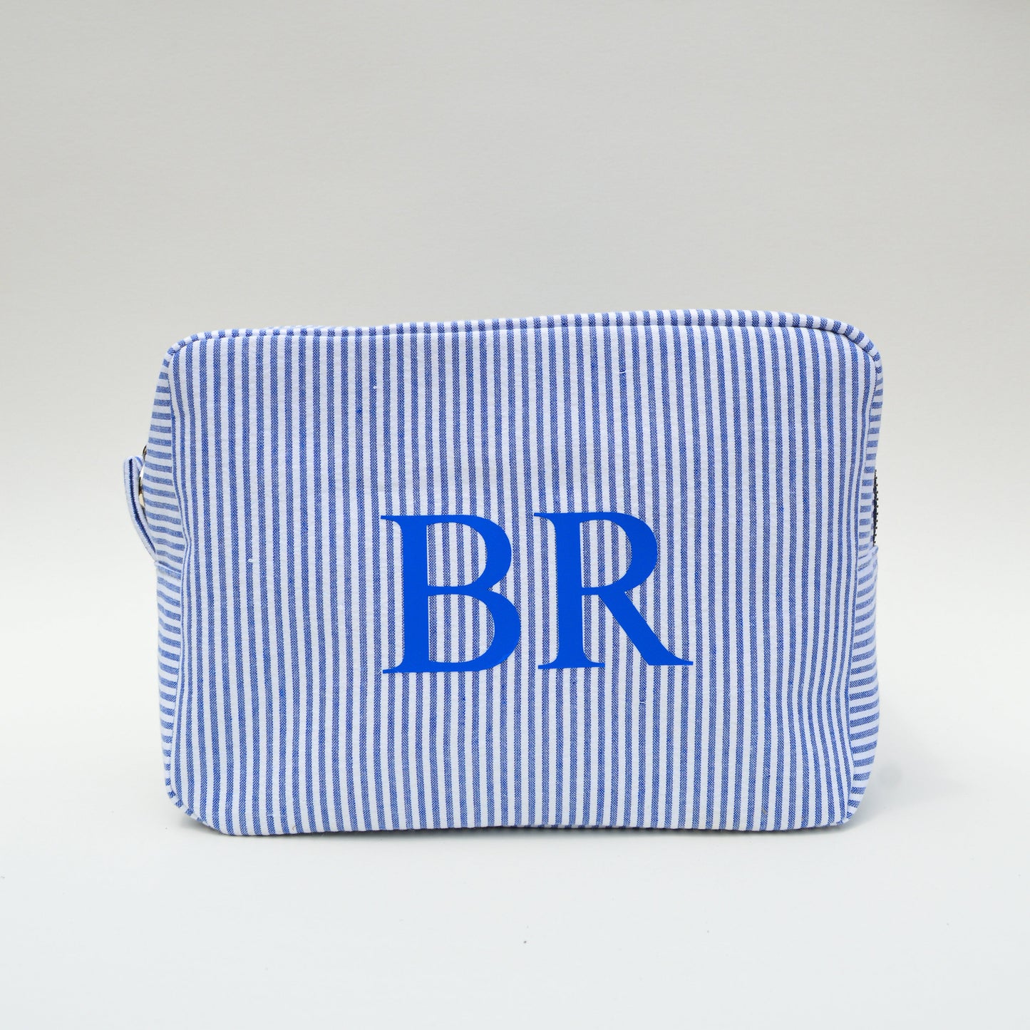 Blue and white striped pouch with 'BR' initials on a light gray background
