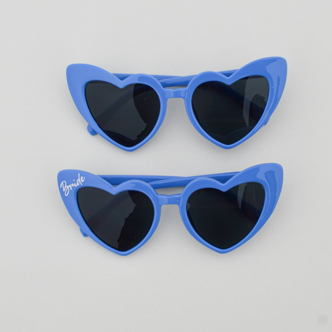 Blue heart-shaped sunglasses on a light gray background