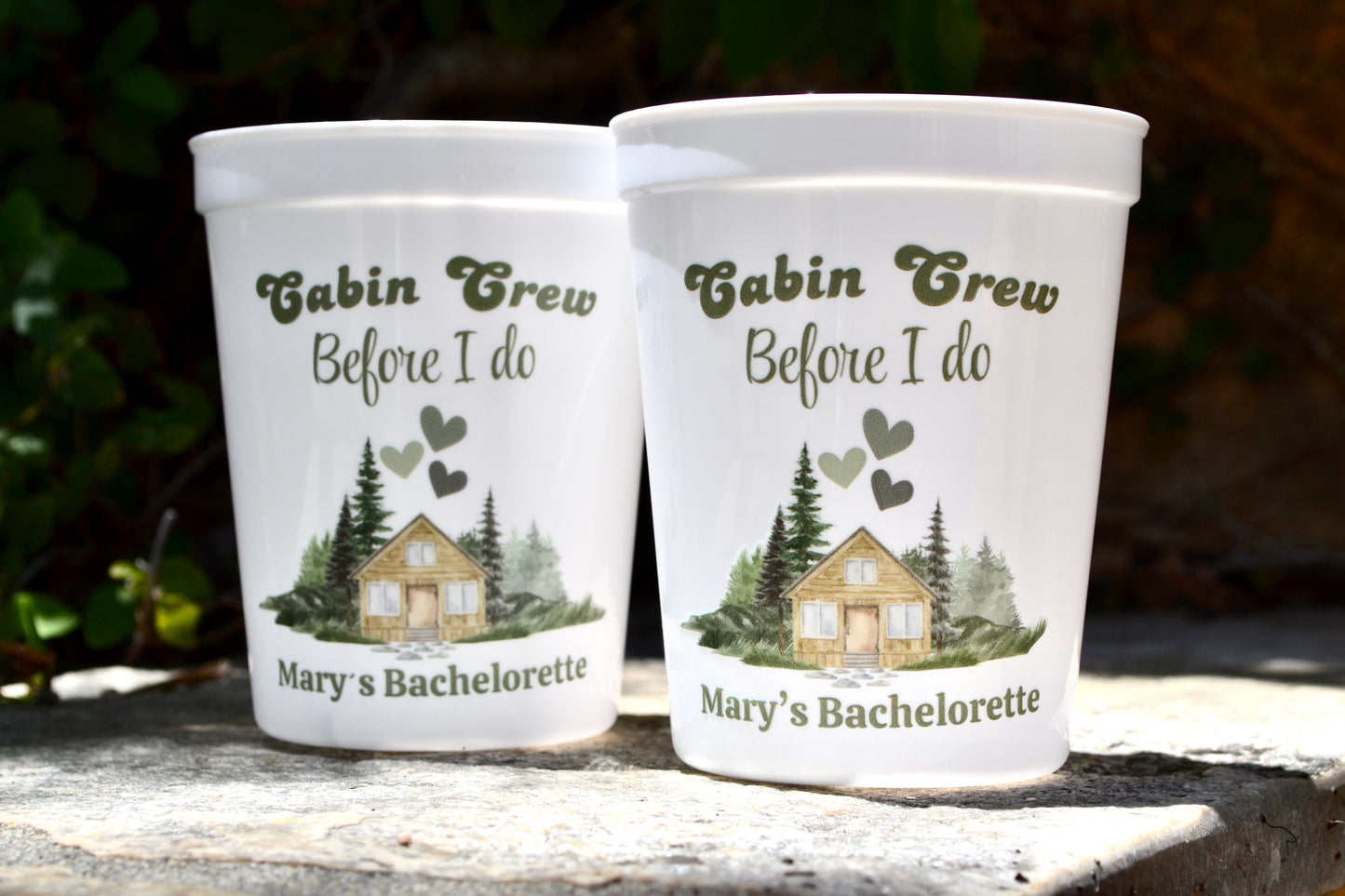 Two white cups with 'Cabin Crew Before I Do' text and nature-themed design on a wooden surface.