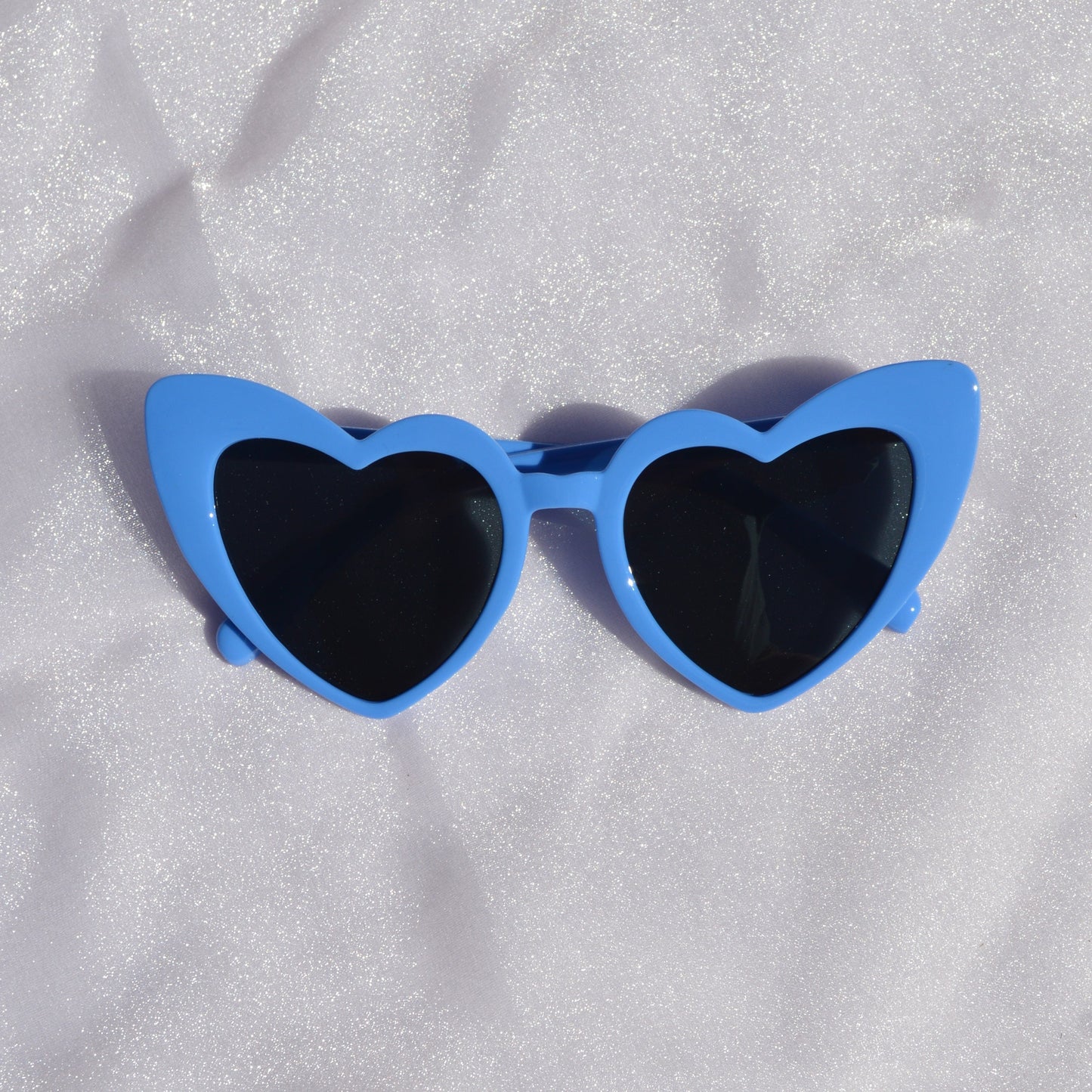 Blue sunglasses with black lenses on a white textured surface