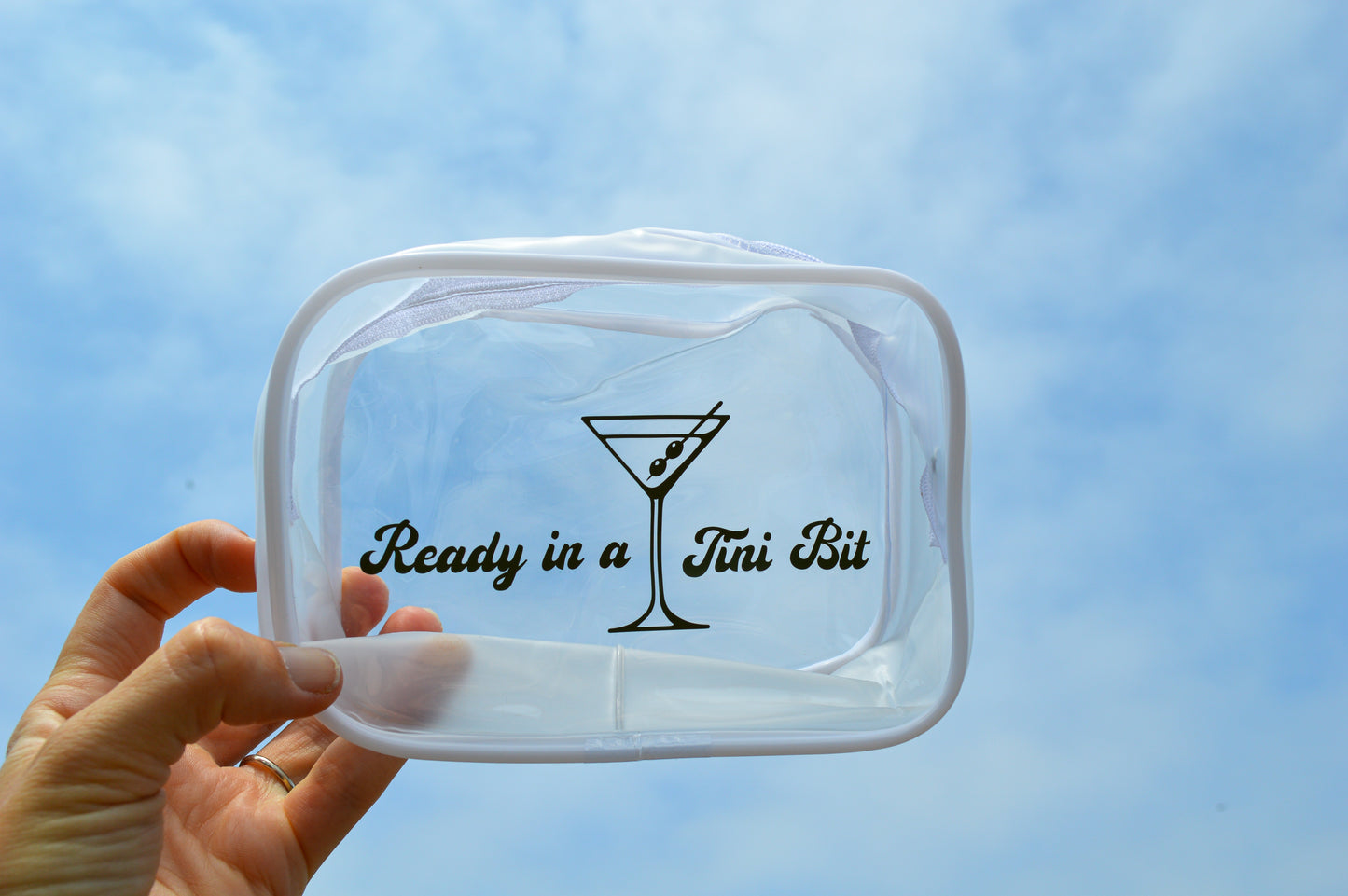 Clear plastic container with 'Ready in a Tini Bit' text and martini glass design against a blue sky.