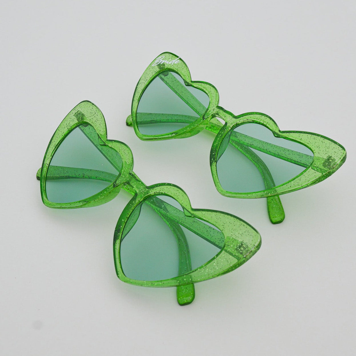 Green heart-shaped sunglasses on a light gray surface