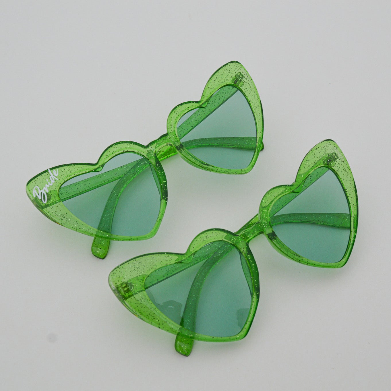 Green sunglasses with transparent frames on a light gray background