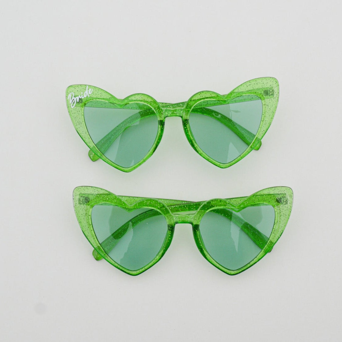 Green heart shaped sunglasses on a light gray background