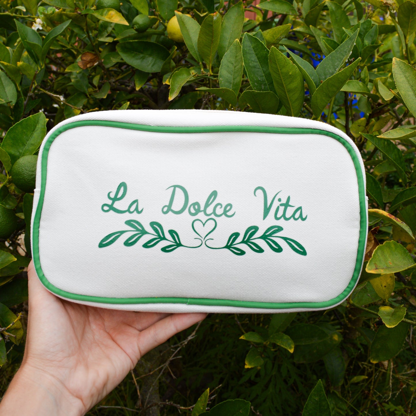 Rectangular pouch with 'La Dolce Vita' text held in front of a lemon tree