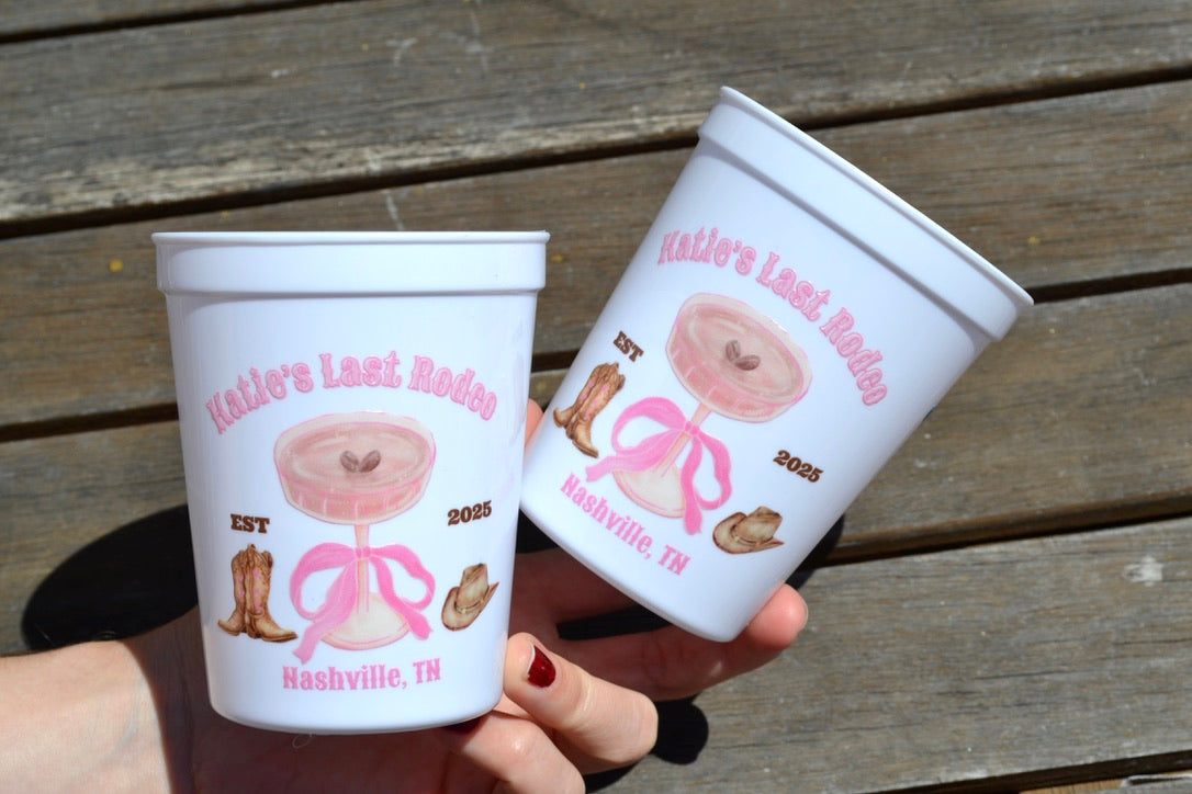 Two personalized plastic cups with decorative designs and text on a wooden surface.