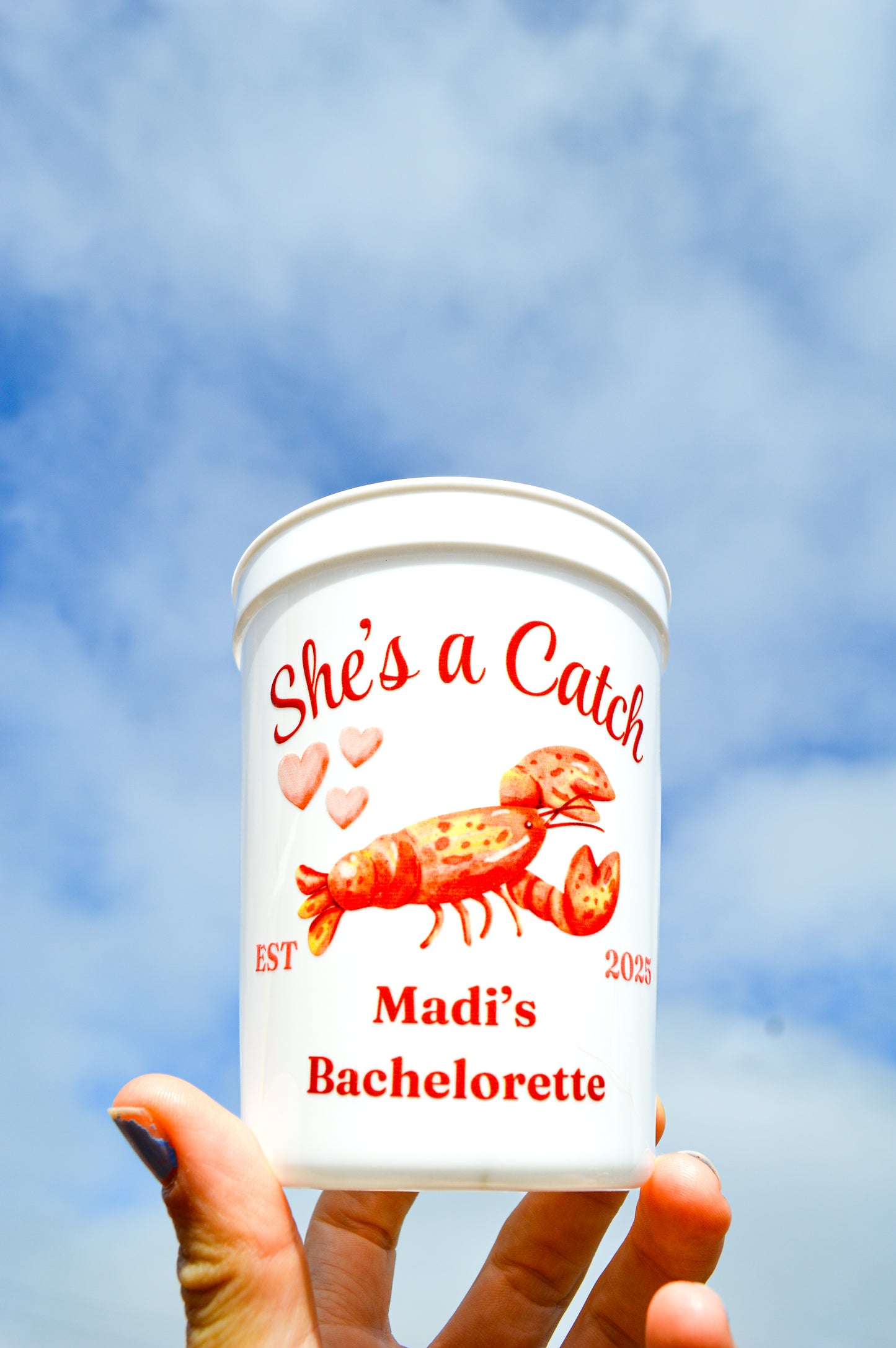 Cup with 'She's a Catch' and 'Madi's Bachelorette' text against a blue sky