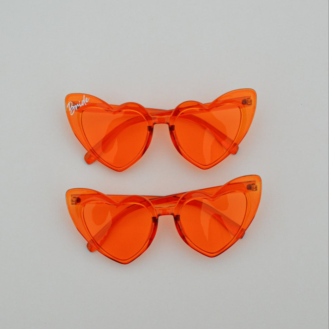 Pair of orange cat-eye sunglasses on a light gray background