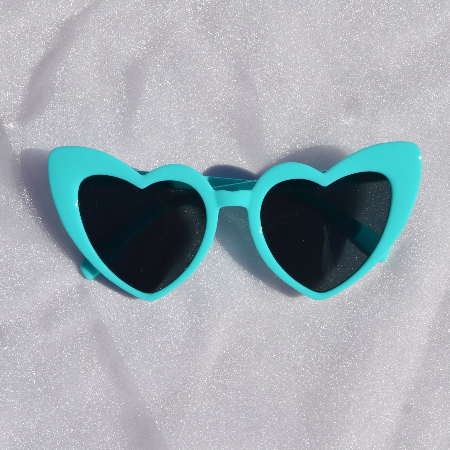 Turquoise sunglasses on a white fabric background
