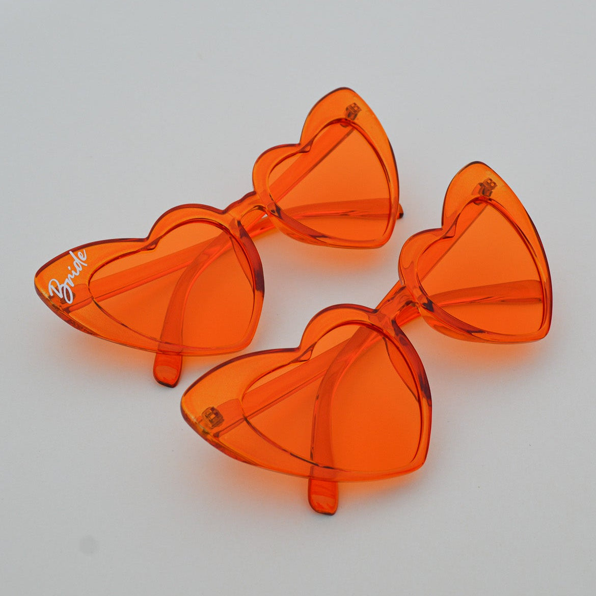 Orange heart-shaped sunglasses on a white surface
