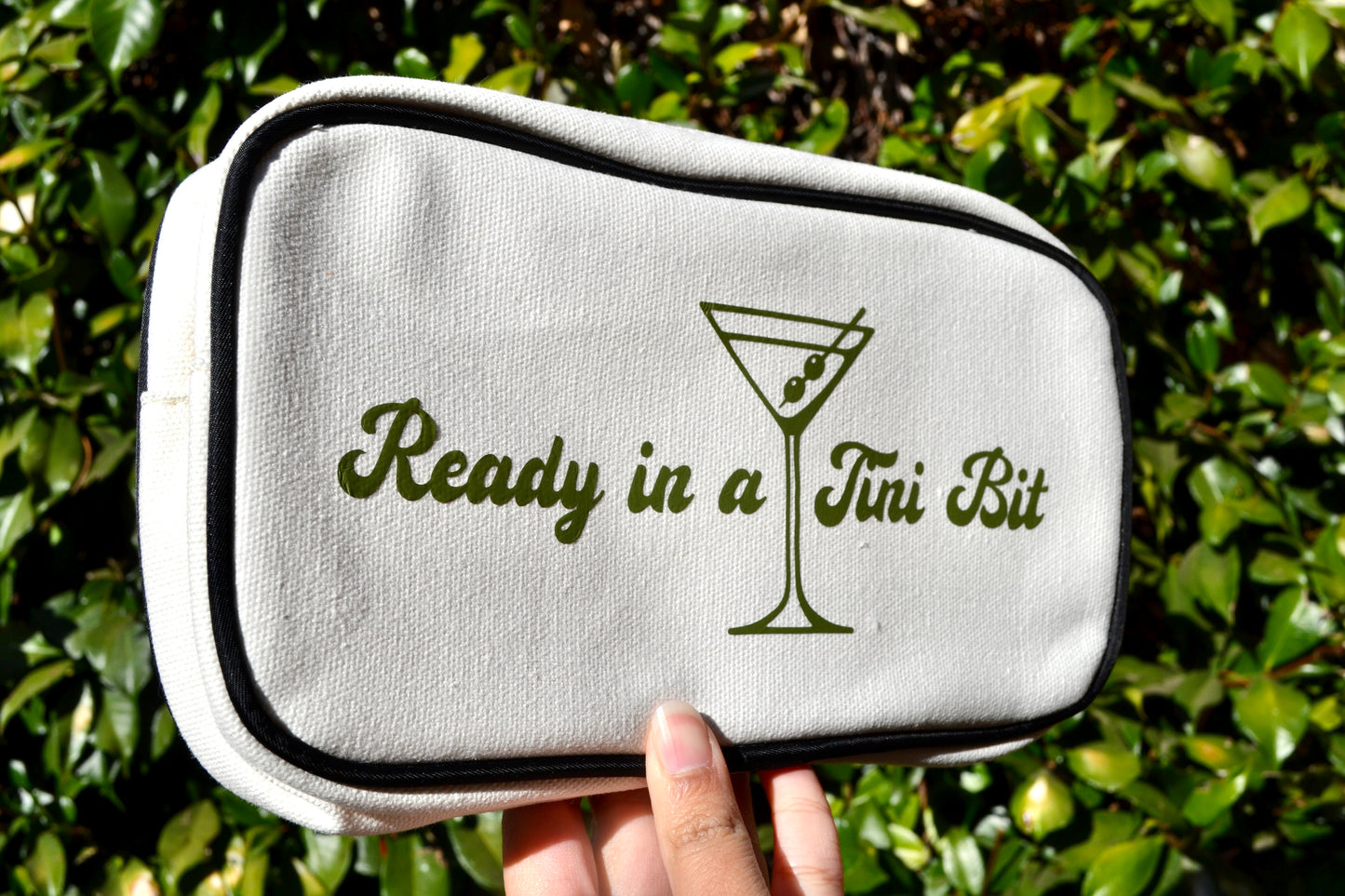 White pouch with 'Ready in a Jui Bit' text and martini glass design held against a green leafy background.