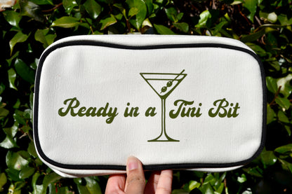 White pouch with 'Ready in a Tini Bit' text and martini glass design held against a green leafy background