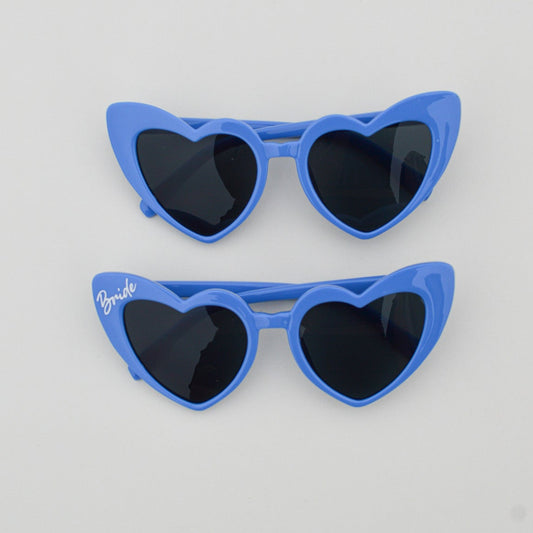 Blue heart-shaped sunglasses on a light gray background