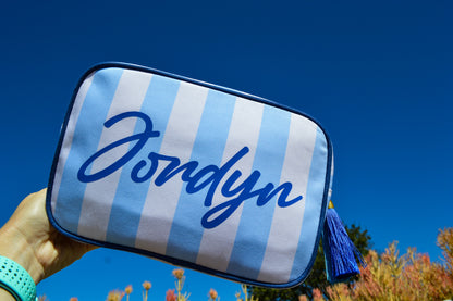 Blue and white striped pouch with 'Jordyn' written on it against a clear blue sky.