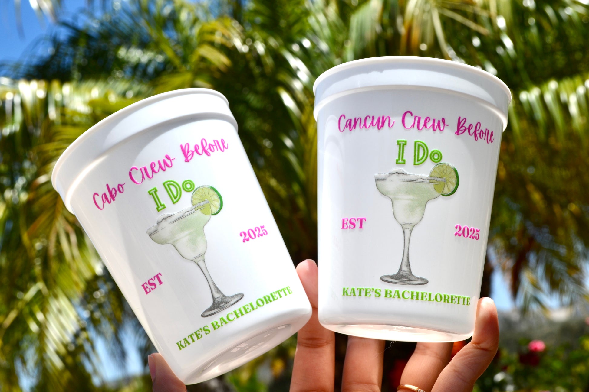 Two cups with personalized designs and text against a blurred natural background