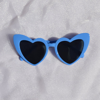 Blue sunglasses with black lenses on a white textured surface