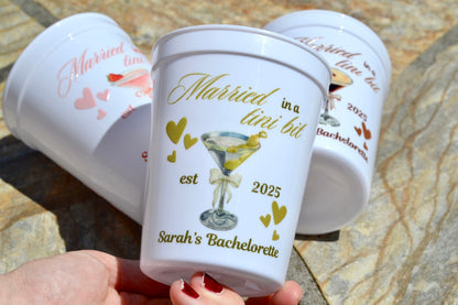 Personalized bachelorette party cups with text and graphics on a stone surface