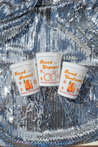 Three cups with printed designs on a sequined surface