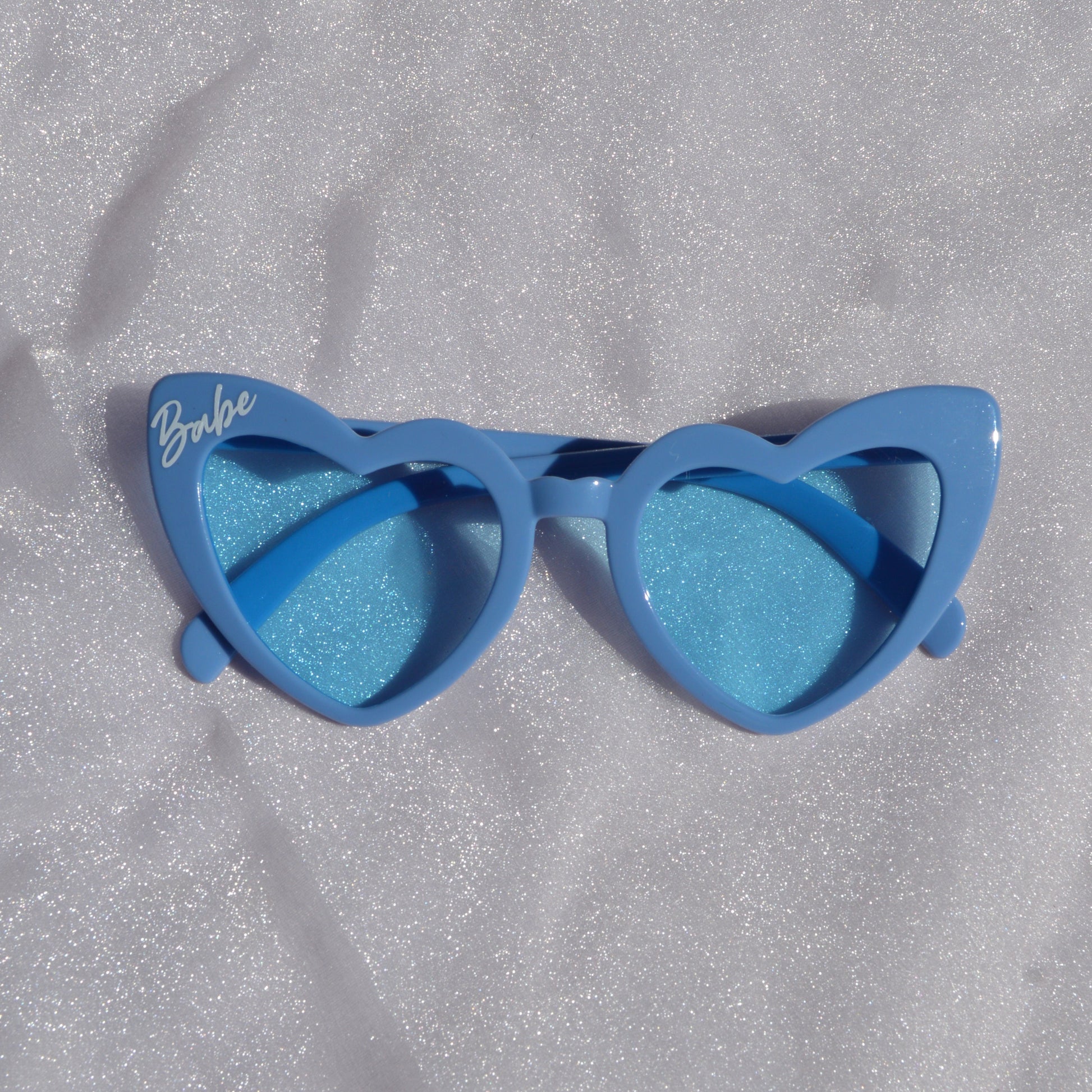 Blue sunglasses with gradient lenses on a textured gray surface