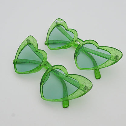 Green heart-shaped sunglasses on a light gray surface