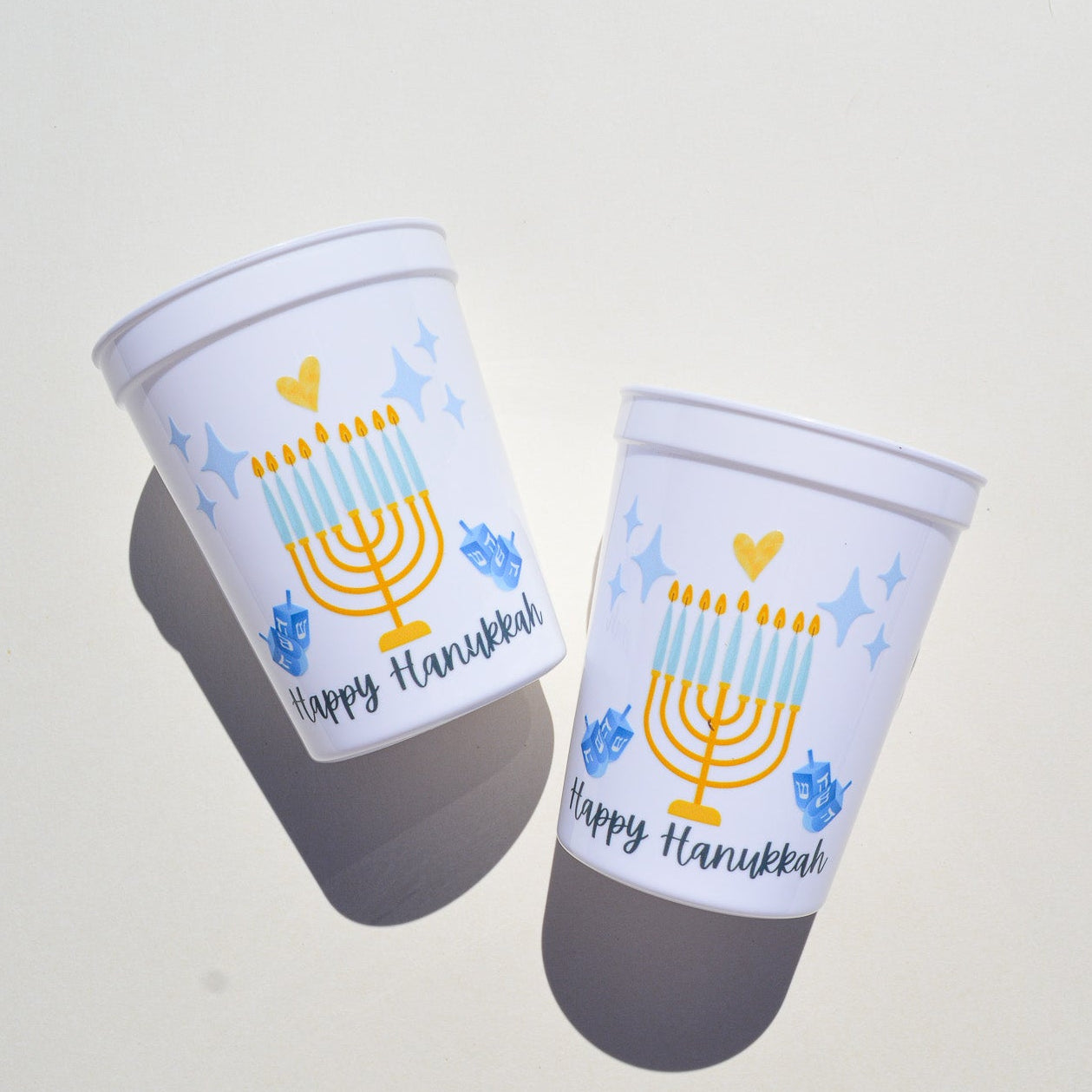 Two cups with Hanukkah-themed designs on a light gray background