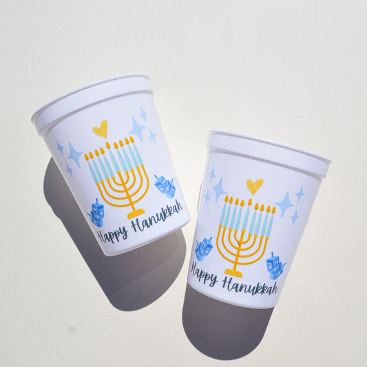 Two cups with Hanukkah-themed designs on a light gray background