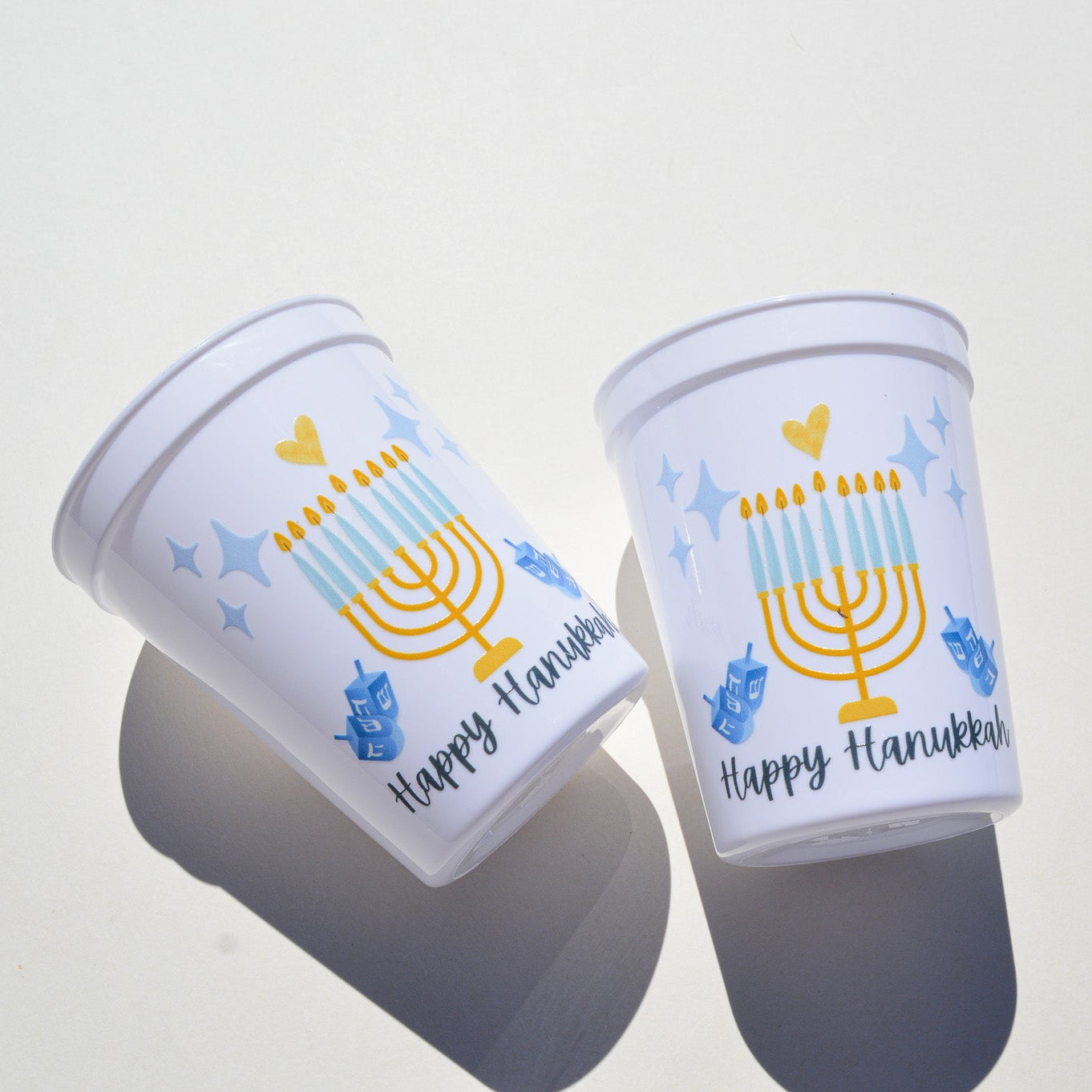 Two white plastic cups with Hanukkah-themed designs on a white background