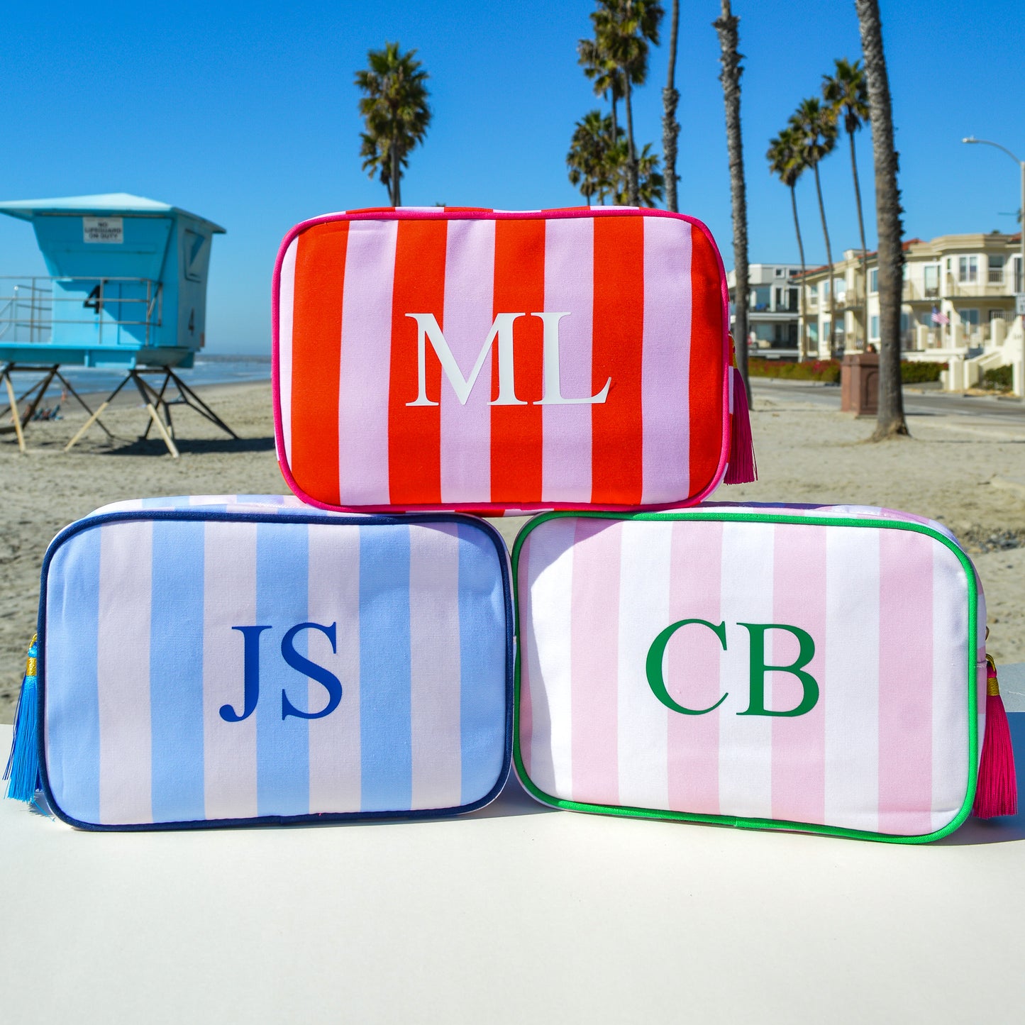 Three striped pouches with initials on a beach