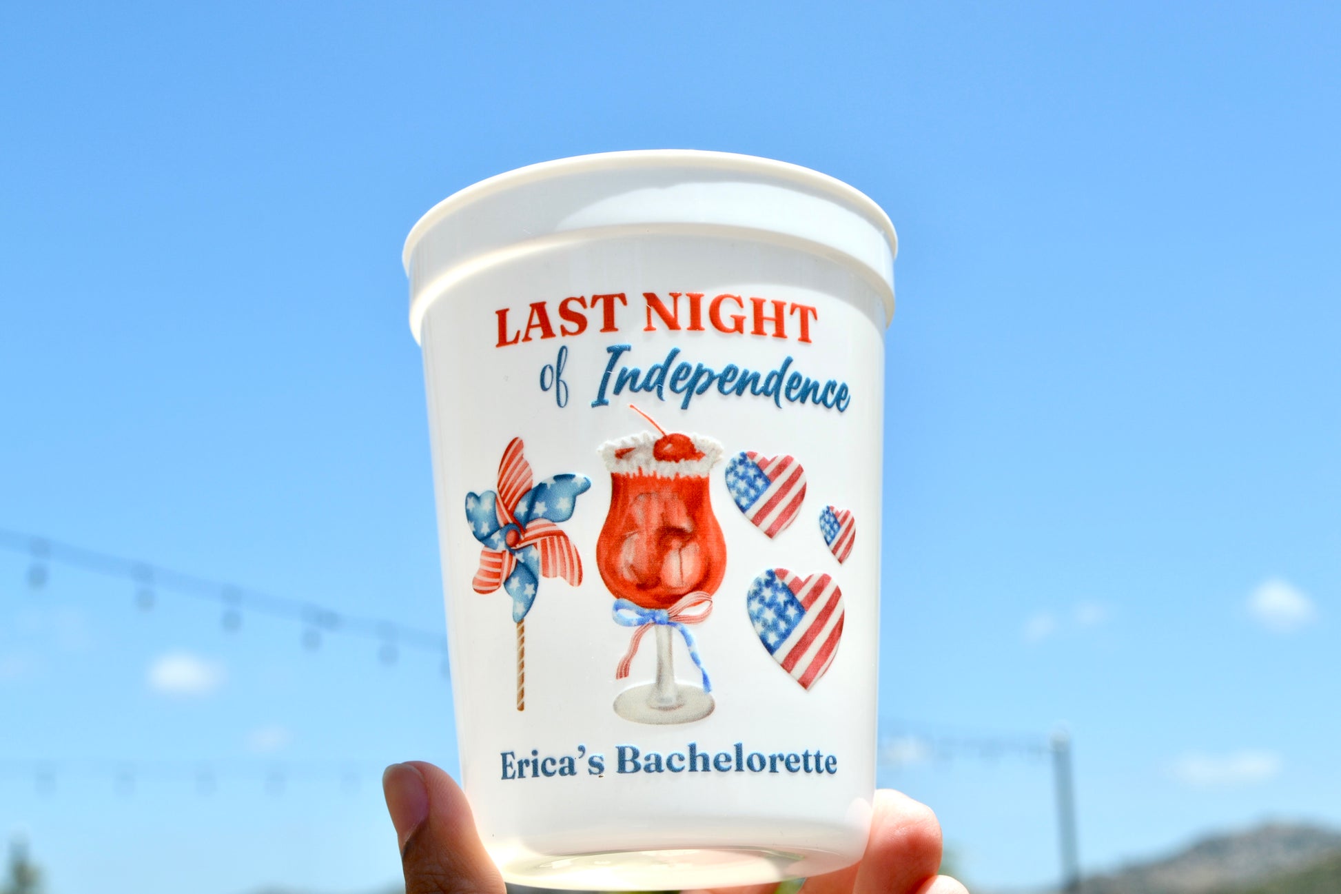 Cup with 'Last Night of Independence' design against a clear blue sky