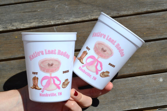 Two personalized plastic cups with decorative designs and text on a wooden surface.