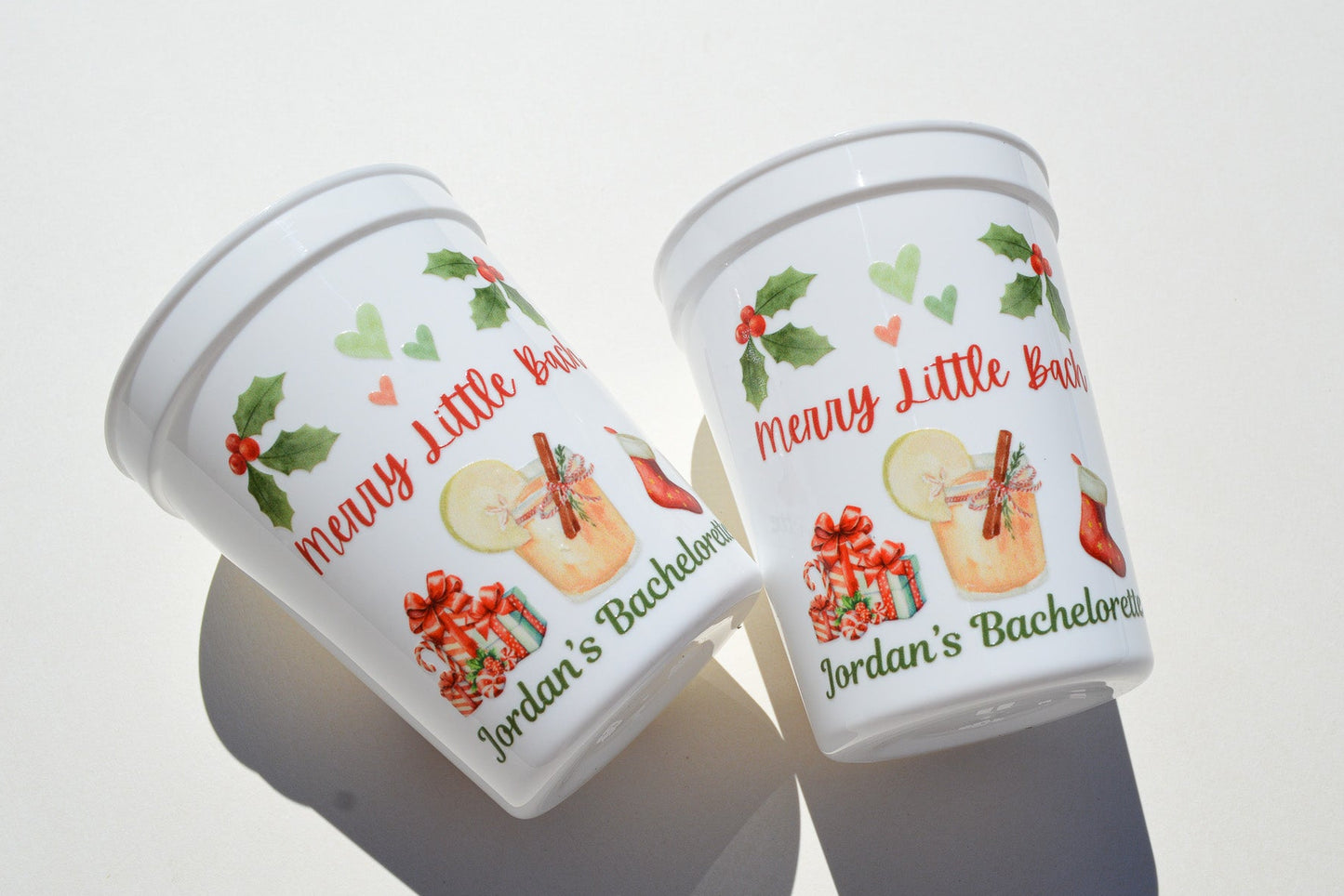 Two festive-themed cups with holiday designs and text on a white background