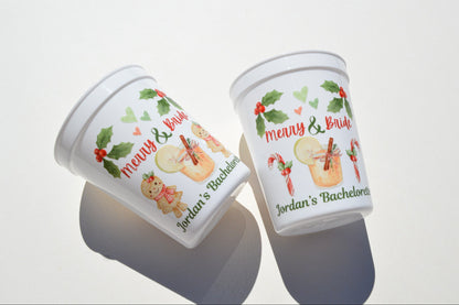 Two Christmas-themed plastic cups with decorative labels on a white surface.