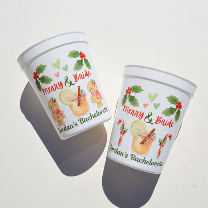 Two white cups with festive designs and text on a white background