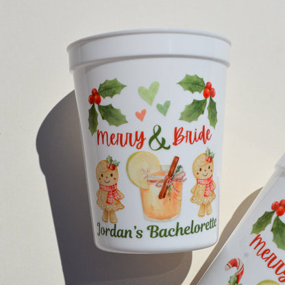 White cup with Christmas-themed design featuring gingerbread men and a drink, labeled 'Merry & Bride'.
