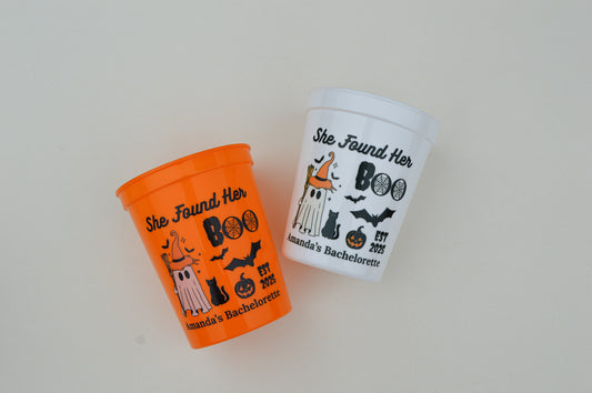 Two Halloween-themed cups with decorative text and graphics on a light gray background.