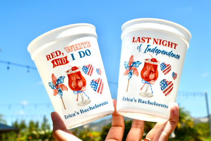 Two personalized bachelorette party cups with patriotic designs against a blue sky.