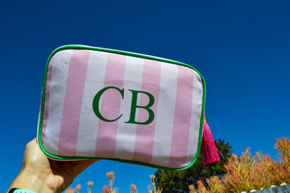 Pink and white striped pouch with 'CB' monogram held against a blue sky.
