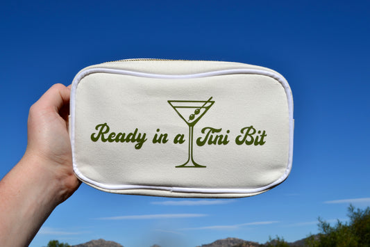 Small pouch with 'Ready in a Tini Bit' text and martini glass design against a blue sky.