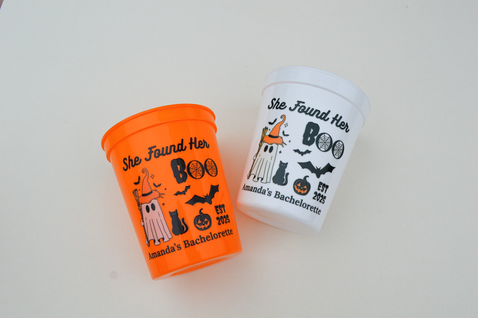 Two Halloween-themed cups with text and graphics on a light background