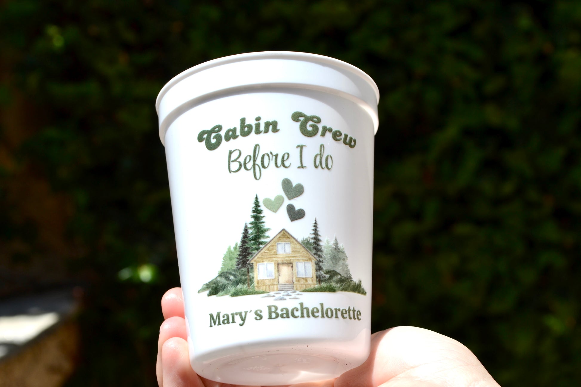 White cup with 'Cabin Crew Before I Do' design held against a blurred green background