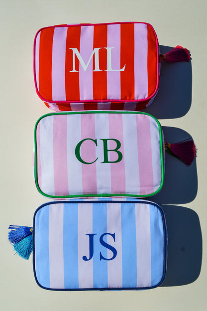 Three striped pouches with initials on a neutral background