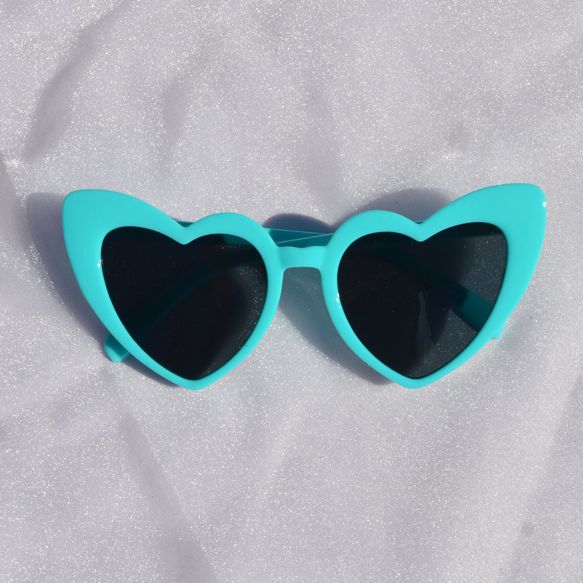Turquoise sunglasses on a white fabric background