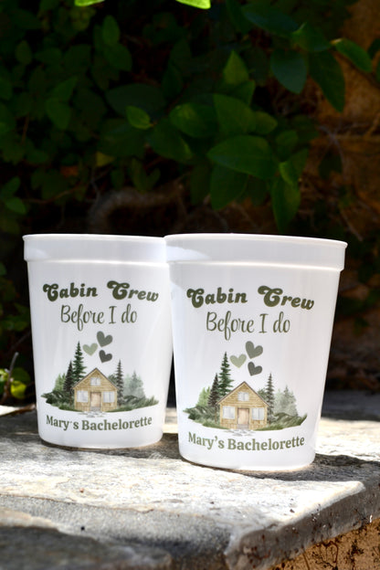 Two personalized cups with 'Cabin Crew Before I Do' design on a stone surface with greenery in the background.